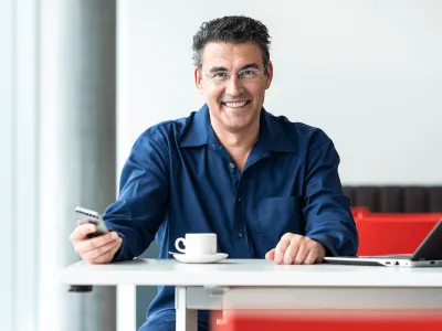 Mann mit Natel am Tisch