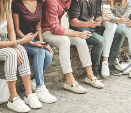 Studierende sitzen auf Mäuerchen